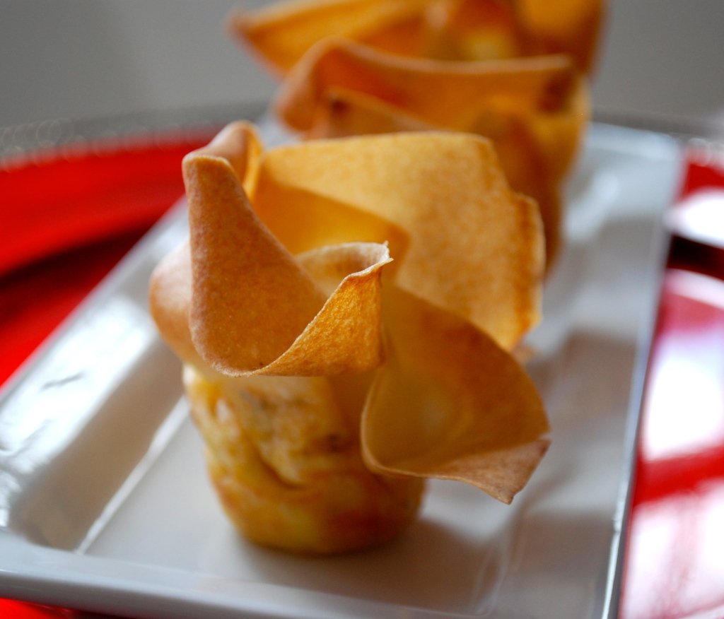 A baked spring roll purse on a white plate filled with goat and cheddar cheese.
